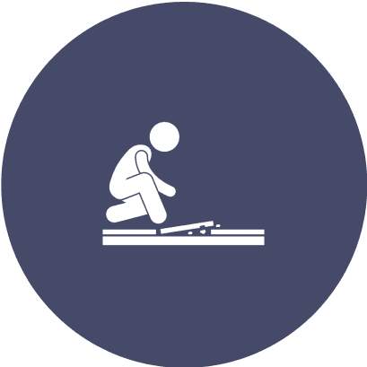 High-Quality Flooring Installation Icon of a person kneeling to lay or repair bricks on the ground, depicted in white on a dark blue circular background.