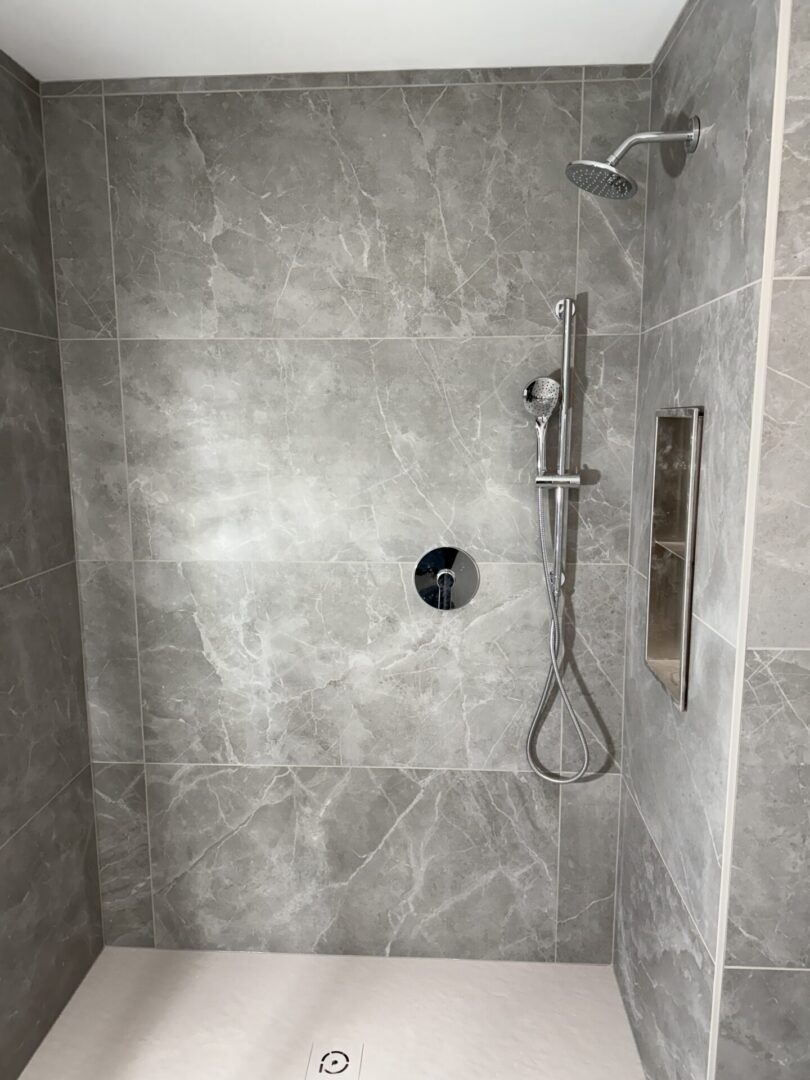 A shower with a black and white tile pattern.