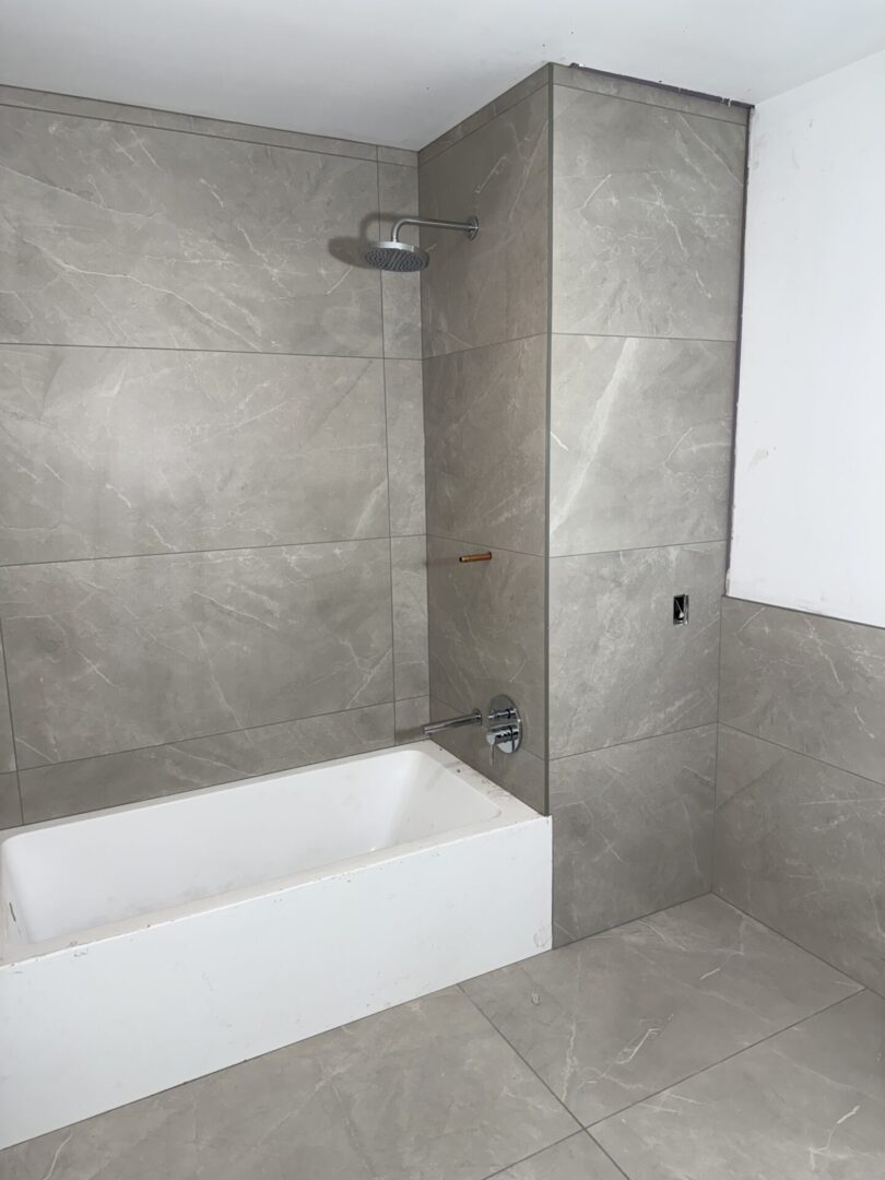 A bathroom with grey tile and white walls.