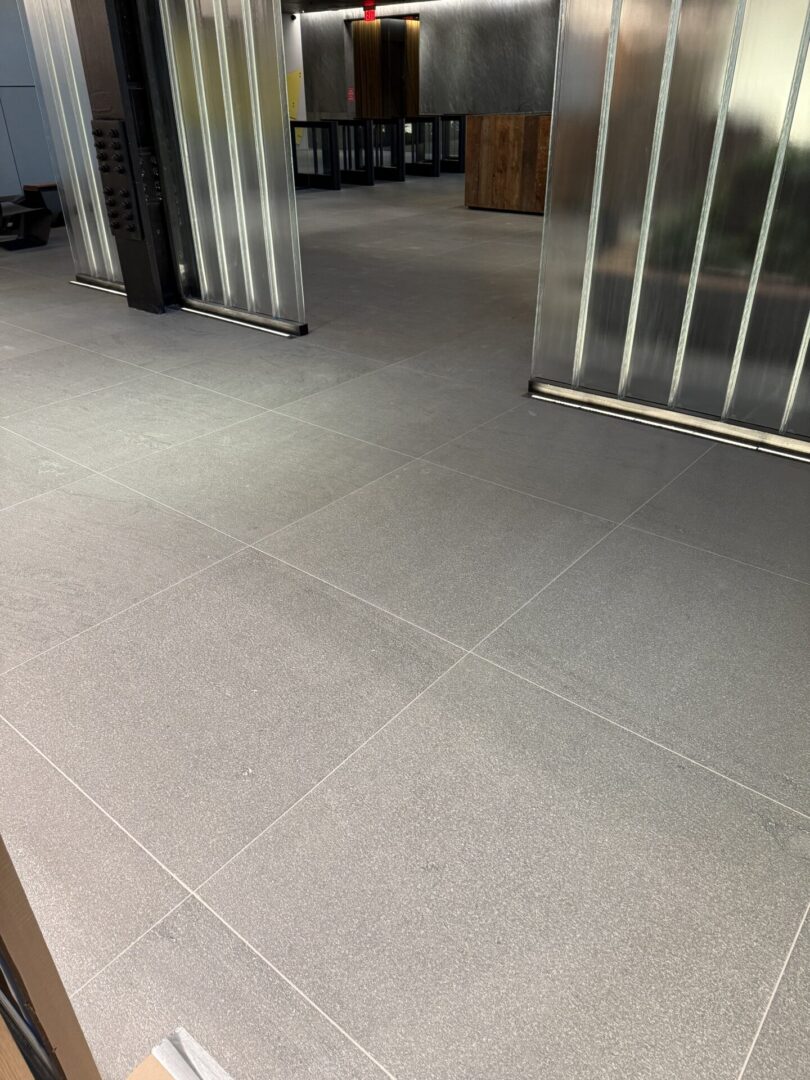 A white tile floor with metal bars in the corner.