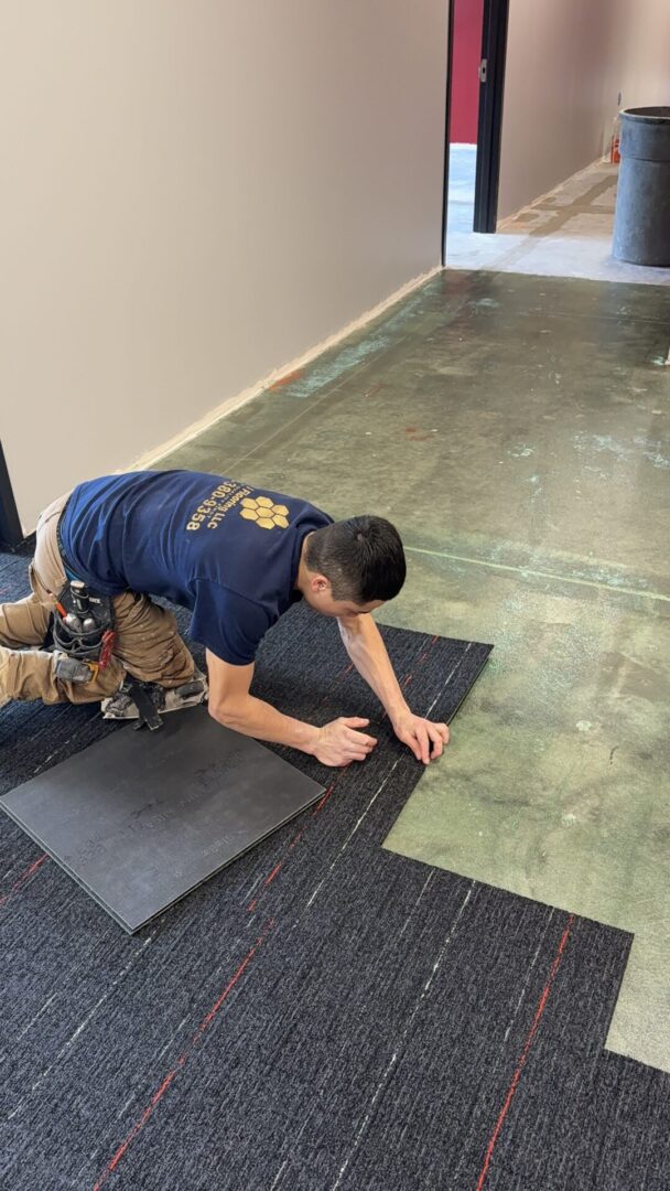 A man laying on the ground working with carpet.