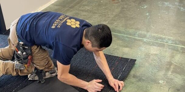 IMG_4730 A man laying on the ground working with carpet.